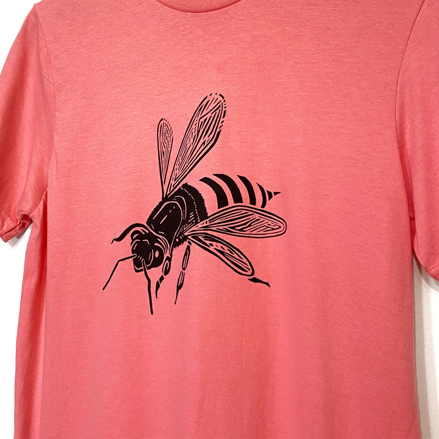 Focus on a black bee on the front of a coral pink tee