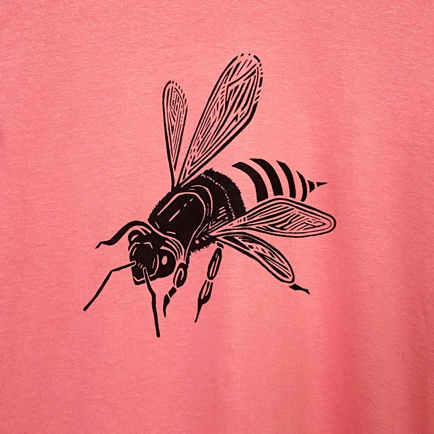 Bee t-shirt design with the bee seen from a 3/4 view on a coral cotton shirt