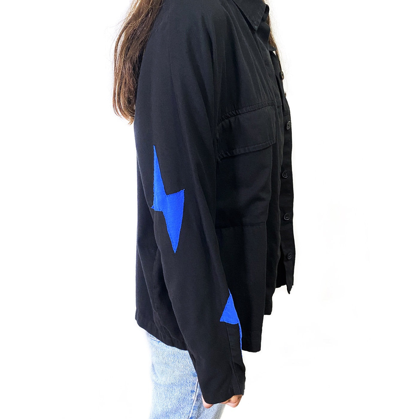 Side view of a person showing the right arm of a black jacket with blue lightening bolts sewn it on with blue stitches