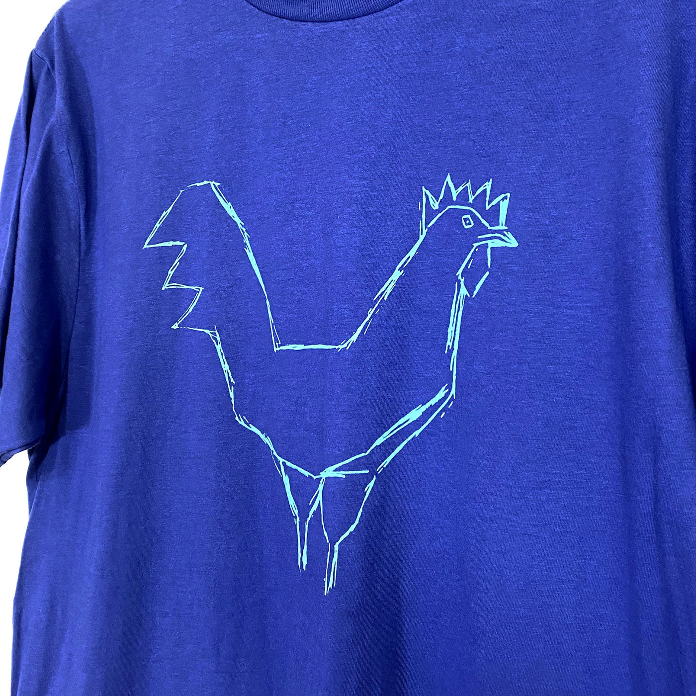 Detail of a light blue loose drawing of a chicken printed on a blue tee