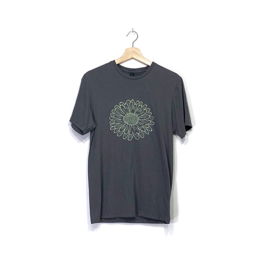 A charcoal grey crew neck short sleeved cotton t-shirt with a silkscreened calendula flower design printed in light green on the front