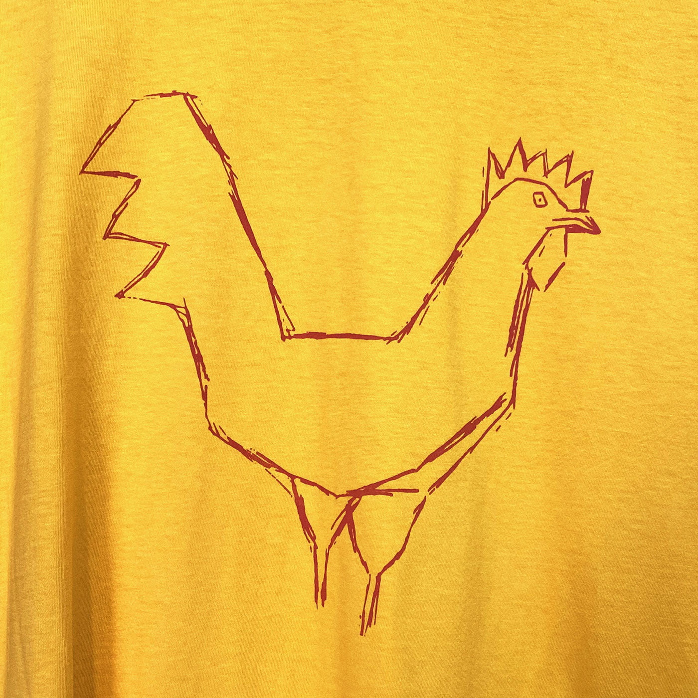 Close up a bright yellow t-shirt printed with a red chicken drawing silkscreen on the front