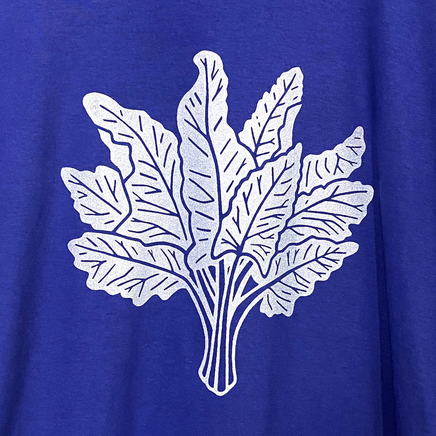 Detail of a silver swiss chard illustration silkscreened on a bright blue tee